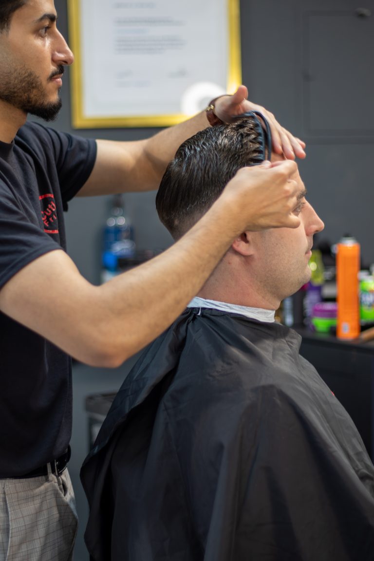 Friseurmeister bei der Arbeit im CutLab Salon, im Hintergrund der gerahmte Meisterbrief